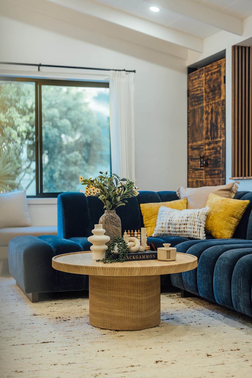 The blue velvet sectional and a round oak coffee table in the living room